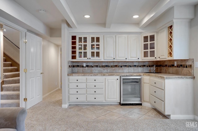 kitchen featuring white cabinetry, wine cooler, decorative backsplash, and light carpet