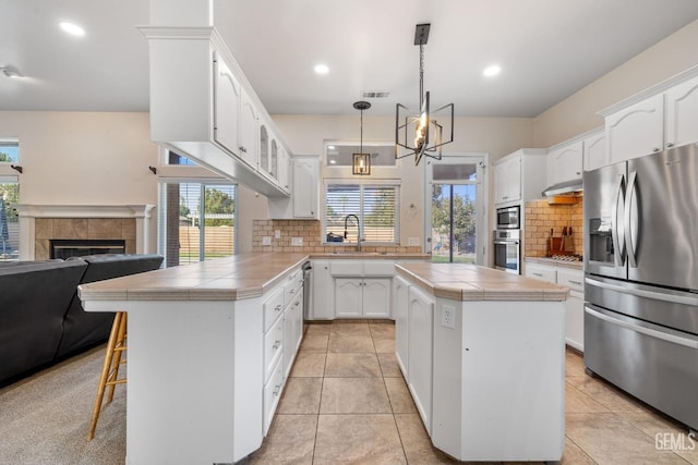 kitchen with tile countertops, visible vents, stainless steel appliances, and a sink