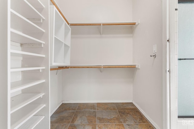 walk in closet featuring stone finish flooring