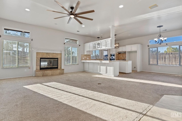 unfurnished living room with baseboards, light colored carpet, a fireplace, a sink, and recessed lighting