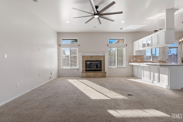 unfurnished living room featuring a tile fireplace, a wealth of natural light, and light colored carpet