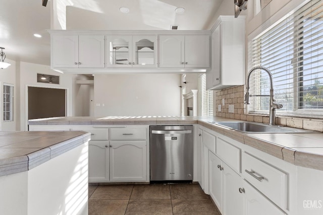 kitchen featuring dishwasher, a peninsula, a sink, and white cabinetry