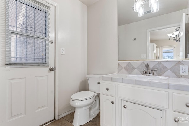 bathroom featuring toilet, tile patterned flooring, backsplash, and vanity