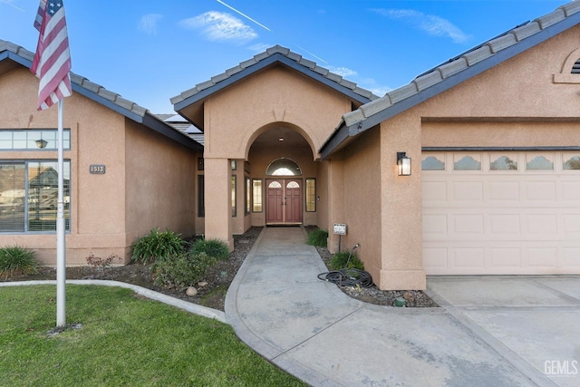 property entrance featuring an attached garage, a tile roof, and stucco siding