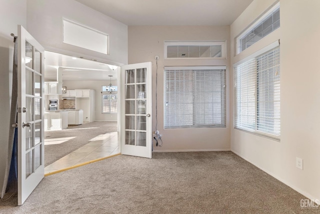 carpeted spare room featuring a chandelier and french doors