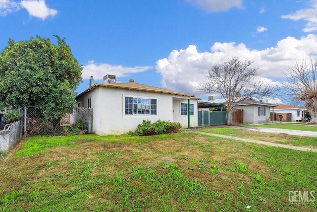 ranch-style house featuring stucco siding, a front lawn, and fence