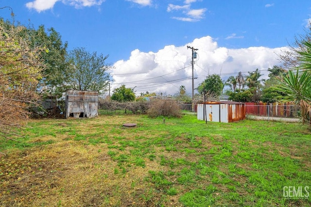 view of yard with a storage shed, an outdoor structure, and fence