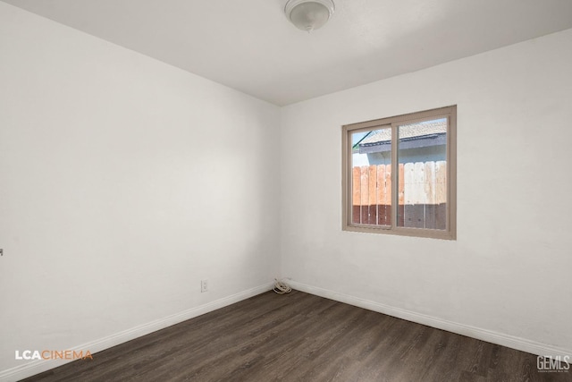 unfurnished room featuring baseboards and dark wood-type flooring