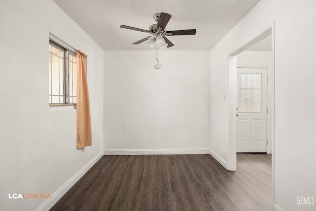 unfurnished room featuring dark wood-style floors, a ceiling fan, and baseboards