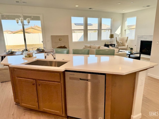 kitchen featuring light hardwood / wood-style floors, sink, stainless steel dishwasher, and an island with sink