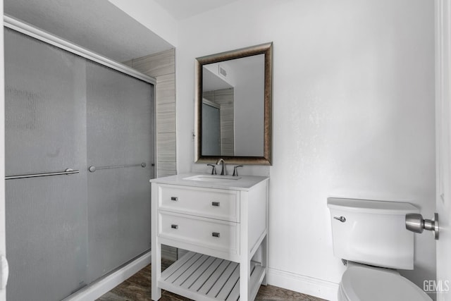 bathroom with a shower with door, vanity, and toilet