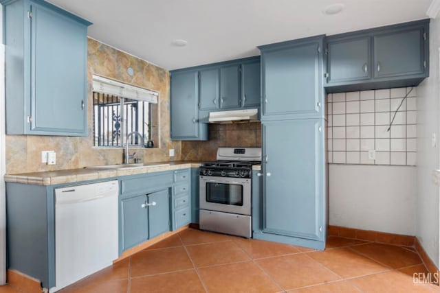 kitchen with white dishwasher, blue cabinets, sink, stainless steel gas range, and light tile patterned floors