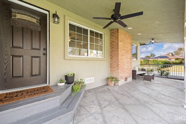 entrance to property with visible vents, covered porch, crawl space, brick siding, and ceiling fan