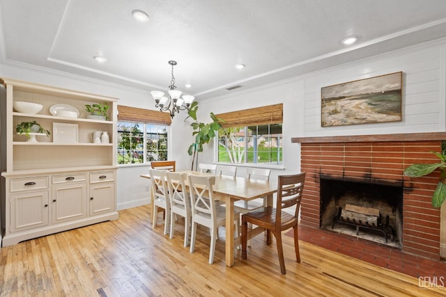 dining room with ornamental molding, plenty of natural light, light wood-type flooring, and a chandelier