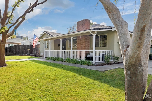 view of side of home featuring fence, a yard, covered porch, stucco siding, and a chimney