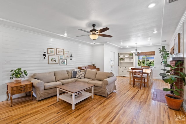 living area with light wood finished floors, visible vents, ceiling fan with notable chandelier, and crown molding