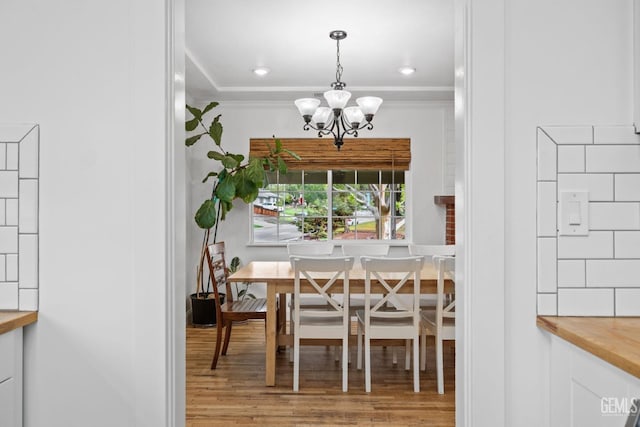 dining space featuring a chandelier, recessed lighting, crown molding, and wood finished floors