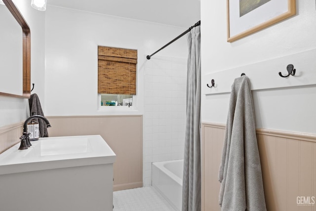 bathroom with vanity, shower / bath combo, and a wainscoted wall