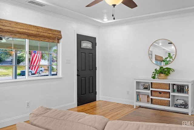 interior space featuring visible vents, wood finished floors, crown molding, baseboards, and ceiling fan