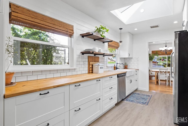 kitchen with butcher block counters, a skylight, tasteful backsplash, and stainless steel appliances