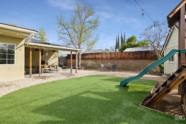 view of yard with a patio, a playground, a ceiling fan, and a fenced backyard