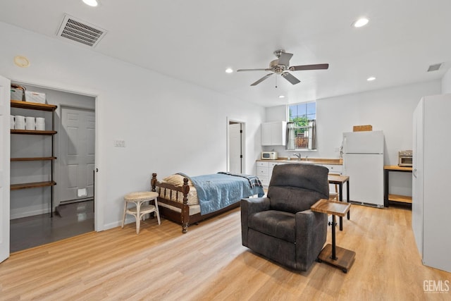 bedroom featuring visible vents, freestanding refrigerator, and light wood-style floors