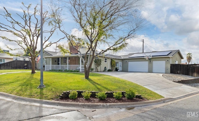 ranch-style house with fence, driveway, solar panels, an attached garage, and a front lawn