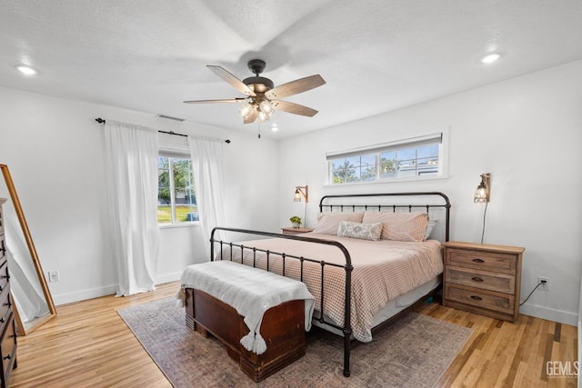 bedroom with baseboards, visible vents, light wood finished floors, recessed lighting, and a textured ceiling