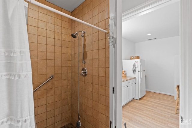 full bathroom with visible vents, wood finished floors, and a shower stall