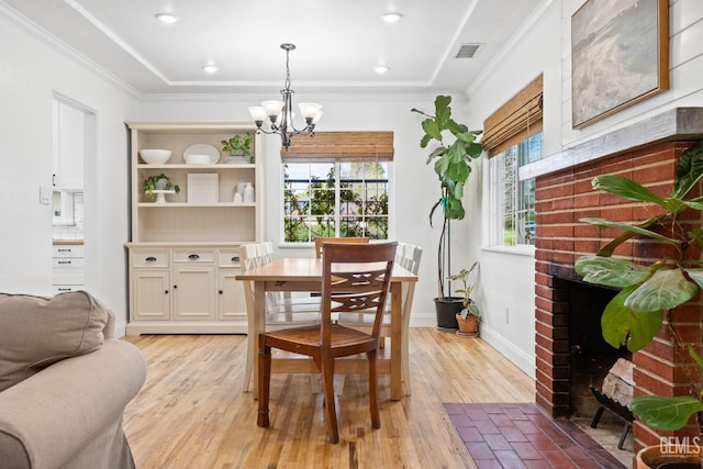 dining room with visible vents, crown molding, light wood-style floors, and an inviting chandelier