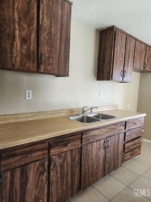 816 Rosa Ct, Delano, CA 93215 - kitchen featuring light countertops, a sink, light tile patterned flooring, dark brown cabinetry, and a textured ceiling