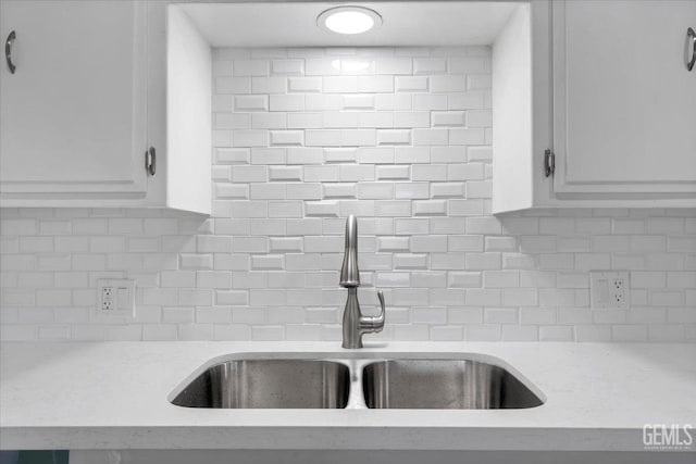 details with white cabinets, backsplash, light stone countertops, and sink