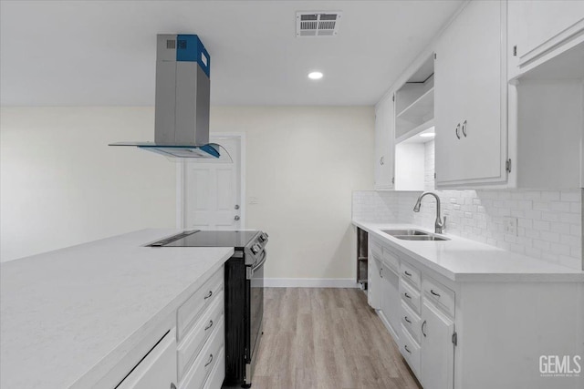 kitchen with electric stove, white cabinetry, sink, and wall chimney exhaust hood