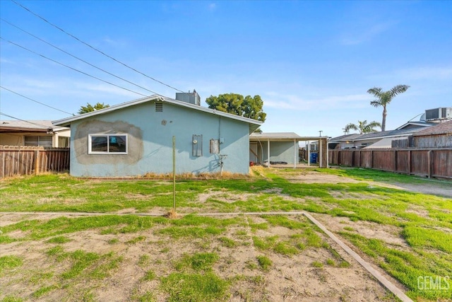 rear view of house featuring a lawn and central AC