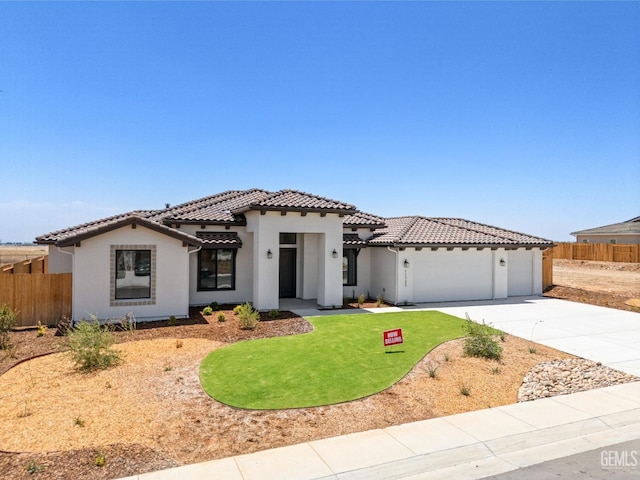 mediterranean / spanish house featuring a tile roof, fence, a garage, and driveway