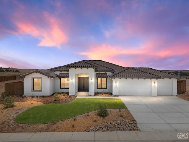 view of front of property with an attached garage, a tile roof, a front yard, stucco siding, and driveway