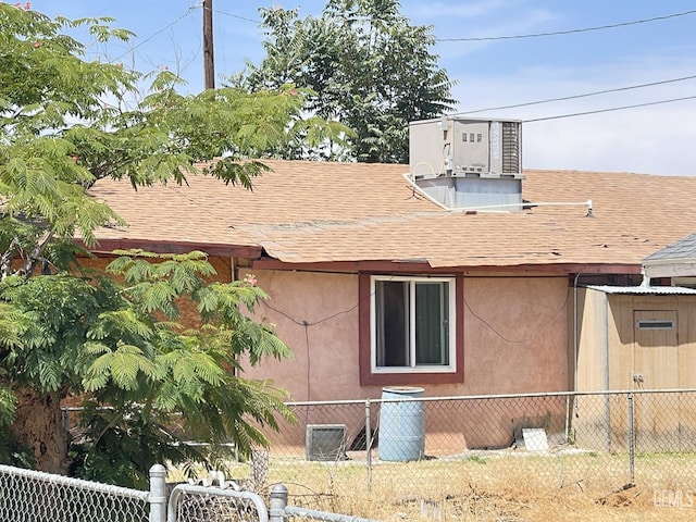 1105 Vansite St, Bakersfield, CA 93307 - view of property exterior featuring a shingled roof, stucco siding, and central air condition unit