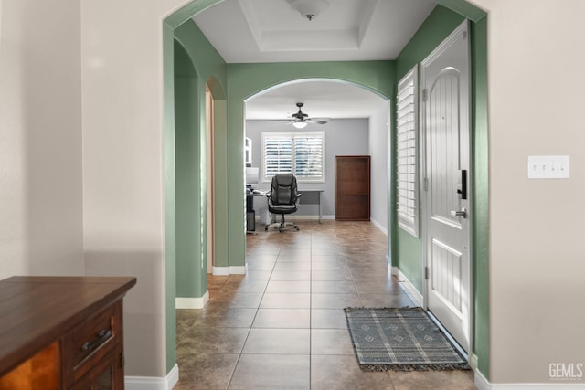 corridor featuring a tray ceiling and tile patterned flooring