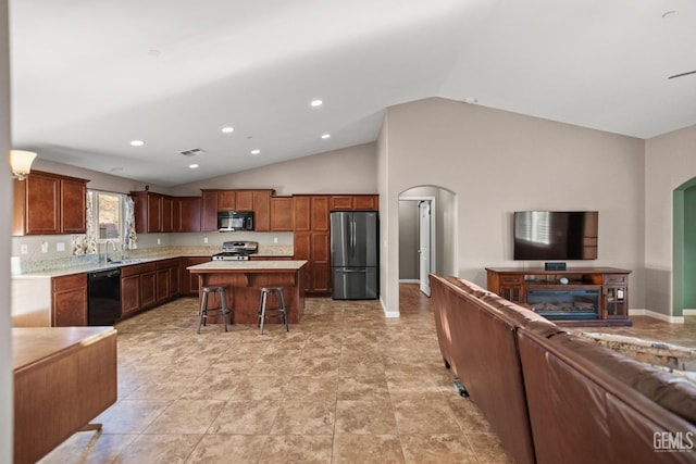 kitchen with a center island, sink, vaulted ceiling, a breakfast bar, and black appliances