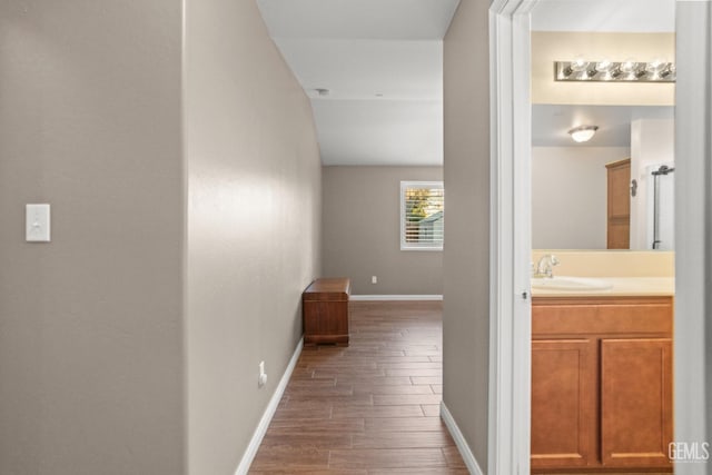 corridor with hardwood / wood-style floors and sink