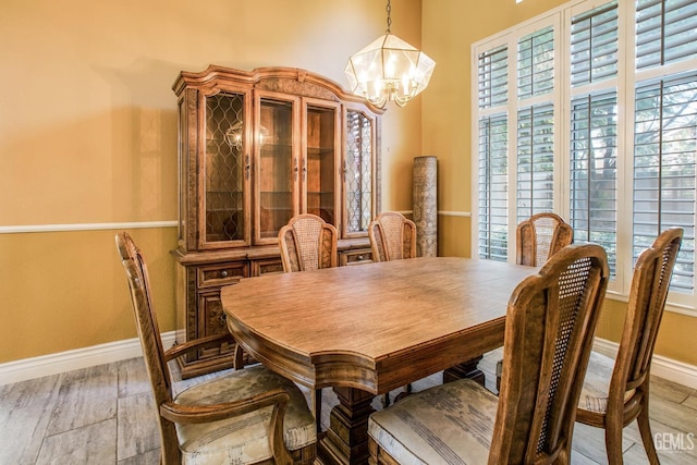 dining area with baseboards, light wood finished floors, and an inviting chandelier