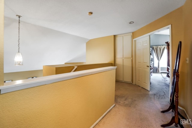 hall with light carpet and vaulted ceiling