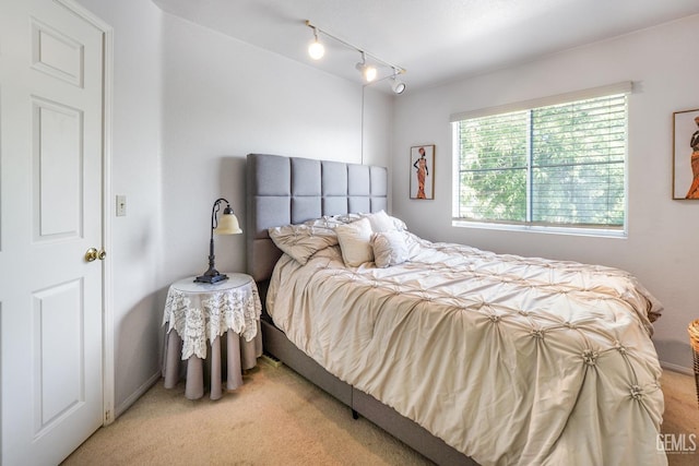 bedroom featuring light carpet and track lighting