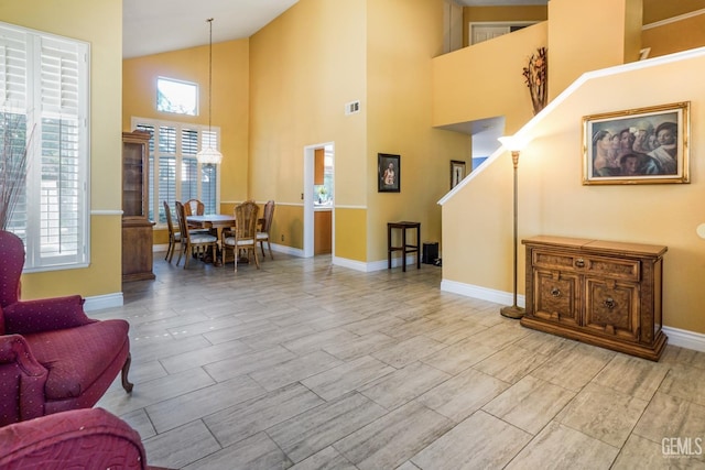 interior space with high vaulted ceiling, visible vents, light wood-style flooring, and baseboards