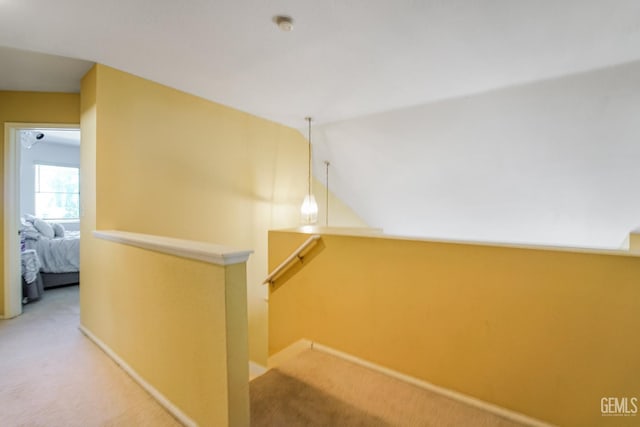 hallway featuring vaulted ceiling, carpet floors, an upstairs landing, and baseboards