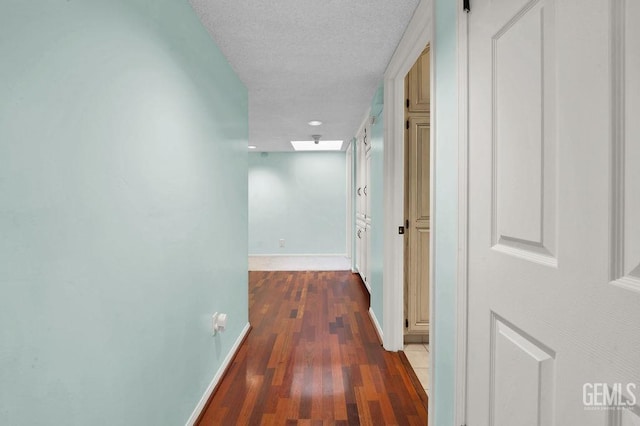 corridor featuring a textured ceiling and dark hardwood / wood-style flooring