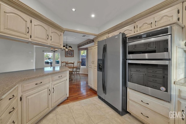 kitchen with light hardwood / wood-style floors, decorative light fixtures, stainless steel appliances, and a notable chandelier