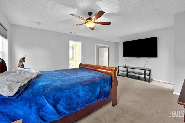 bedroom featuring ceiling fan, ensuite bath, carpet floors, and a textured ceiling