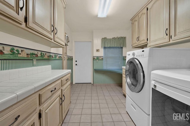 laundry room featuring cabinets, light tile patterned floors, and washing machine and clothes dryer