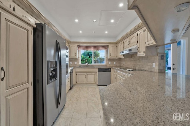 kitchen with kitchen peninsula, decorative backsplash, sink, light stone countertops, and appliances with stainless steel finishes